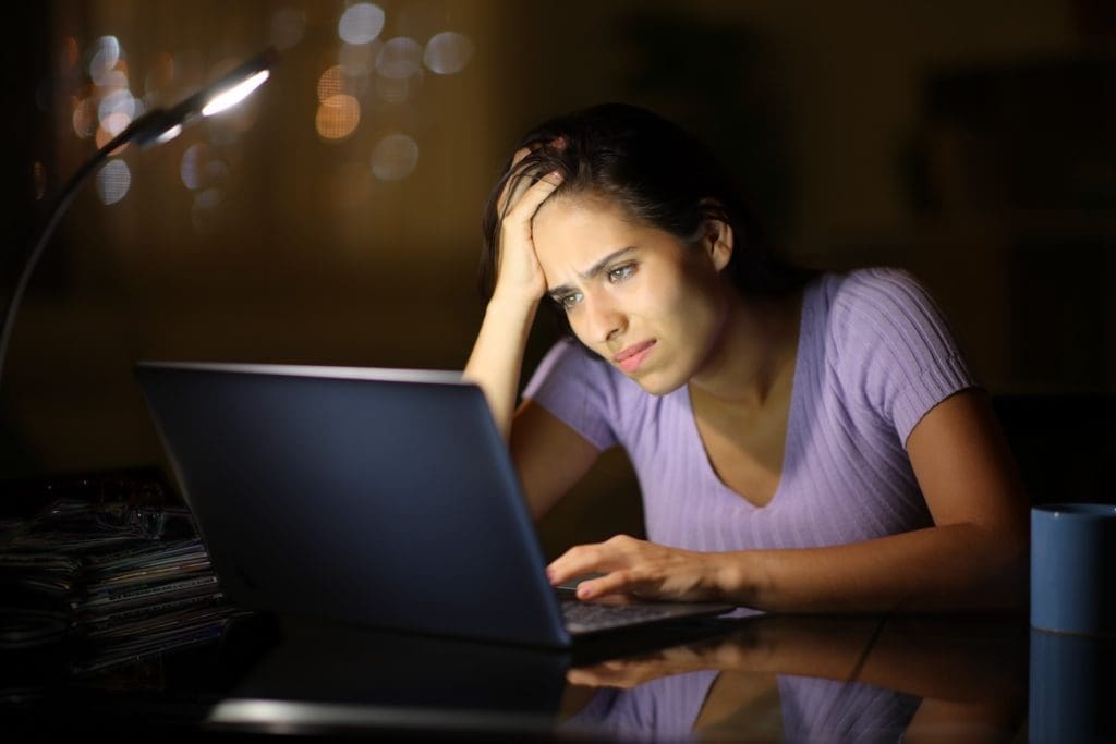 A woman working on a laptop at night, striving to remove negative google search results.