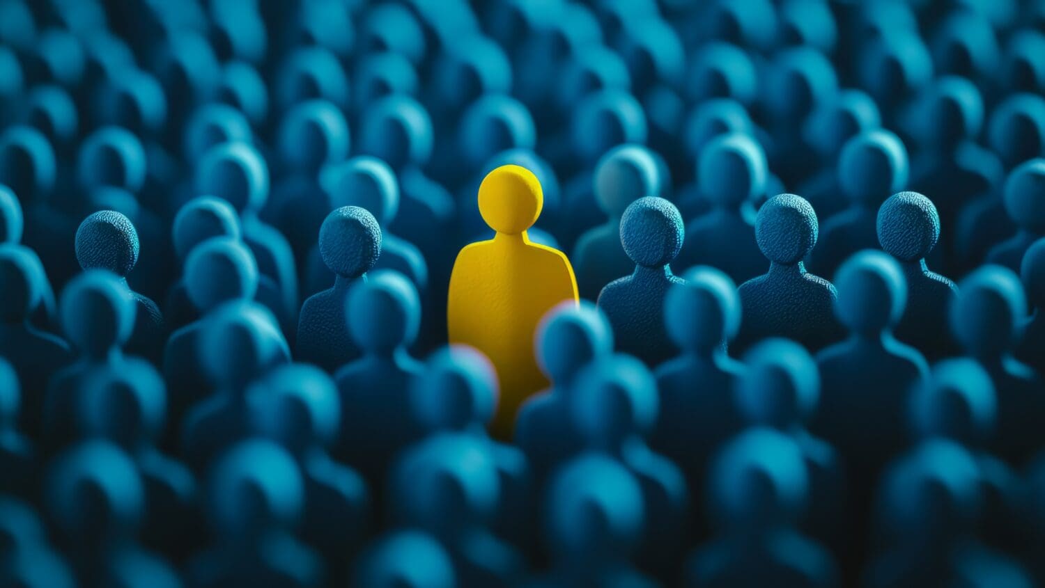 A yellow figure stands out among a crowd of blue figures, symbolizing individuality and uniqueness in a uniform group. The contrast highlights the theme of standing out or being different.