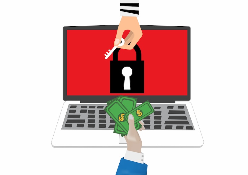 A hand holding a key hovers over a laptop screen displaying a red padlock, while another hand extends cash toward the laptop. This image symbolizes online extortion, highlighting the sinister concept of a ransomware transaction or digital security breach.